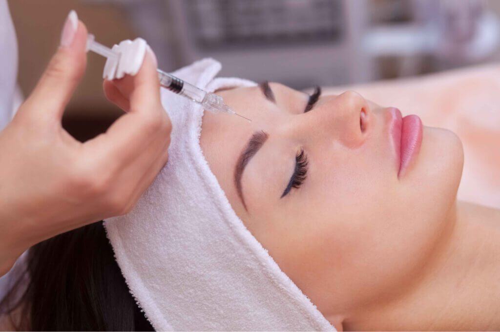 Caucasian women undergoing beauty spa botulinum neurotoxin Botox treatment for anti-aging, to smooth wrinkles as a cometic solution. Injecting forehead to relax muscles with a non-invasive procedure | SavvyDerm Skin Clinic in Millville DE