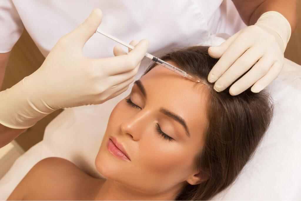 Cosmetologist holding syringe and woman's head in hands Getting Non Surgical Hair Restoration treatment | SavvyDerm Skin Clinic in Millville DE